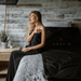 Woman sitting on a bed with a black sauna blanket featuring 'HEALIX' branding.