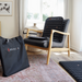 Black HEALX chair and carrying bag in a room with a window and rug.