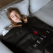 Woman lying on a couch with a black HEALIX blanket draped over her