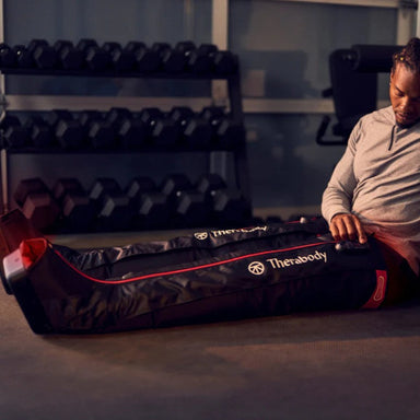 Person using a Therabody massage roller in a gym setting