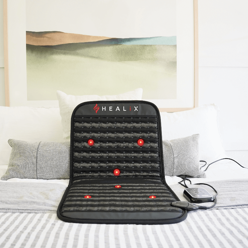 Healix massage mat on a bed with a scenic painting in the background