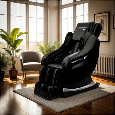 Black massage chair in a room with large windows and plants