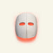 White facial device with red lights on a beige background