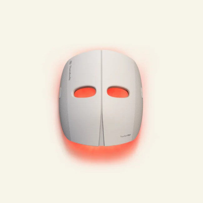 White facial device with red lights on a beige background
