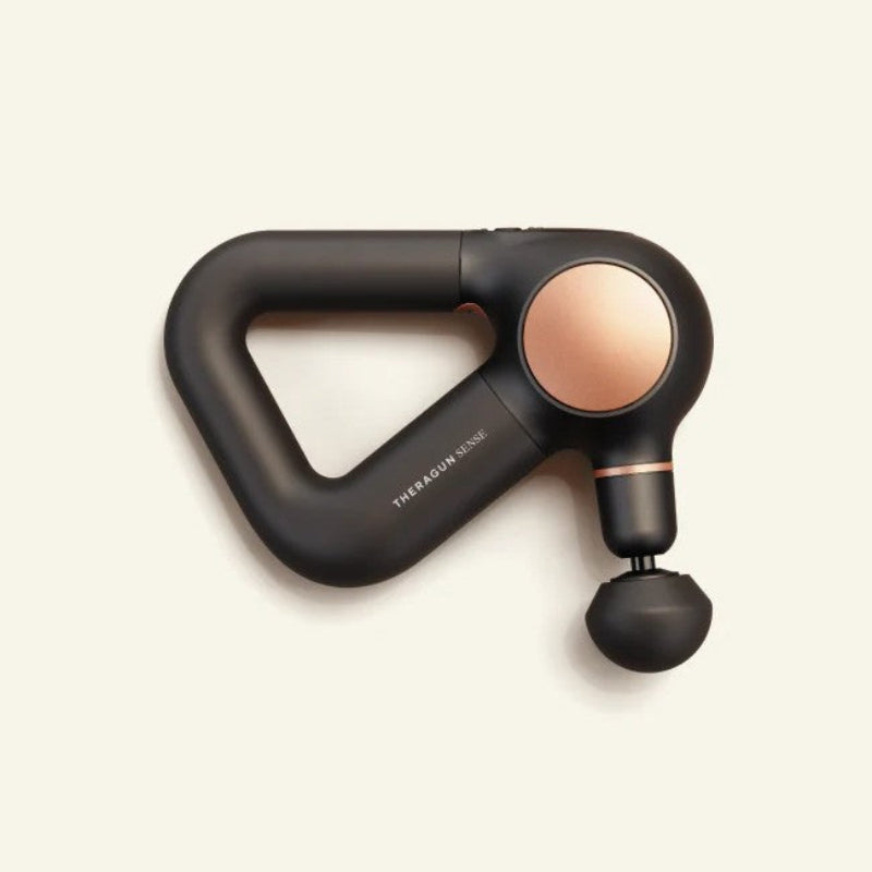 Black and rose gold massage tool on a beige background