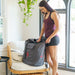 Woman unpacking a gray bag with a visible brand logo in a bright room.
