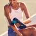 Woman using a massage gun on her arm outdoors