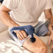 Person using a blue handheld massager on their knee.